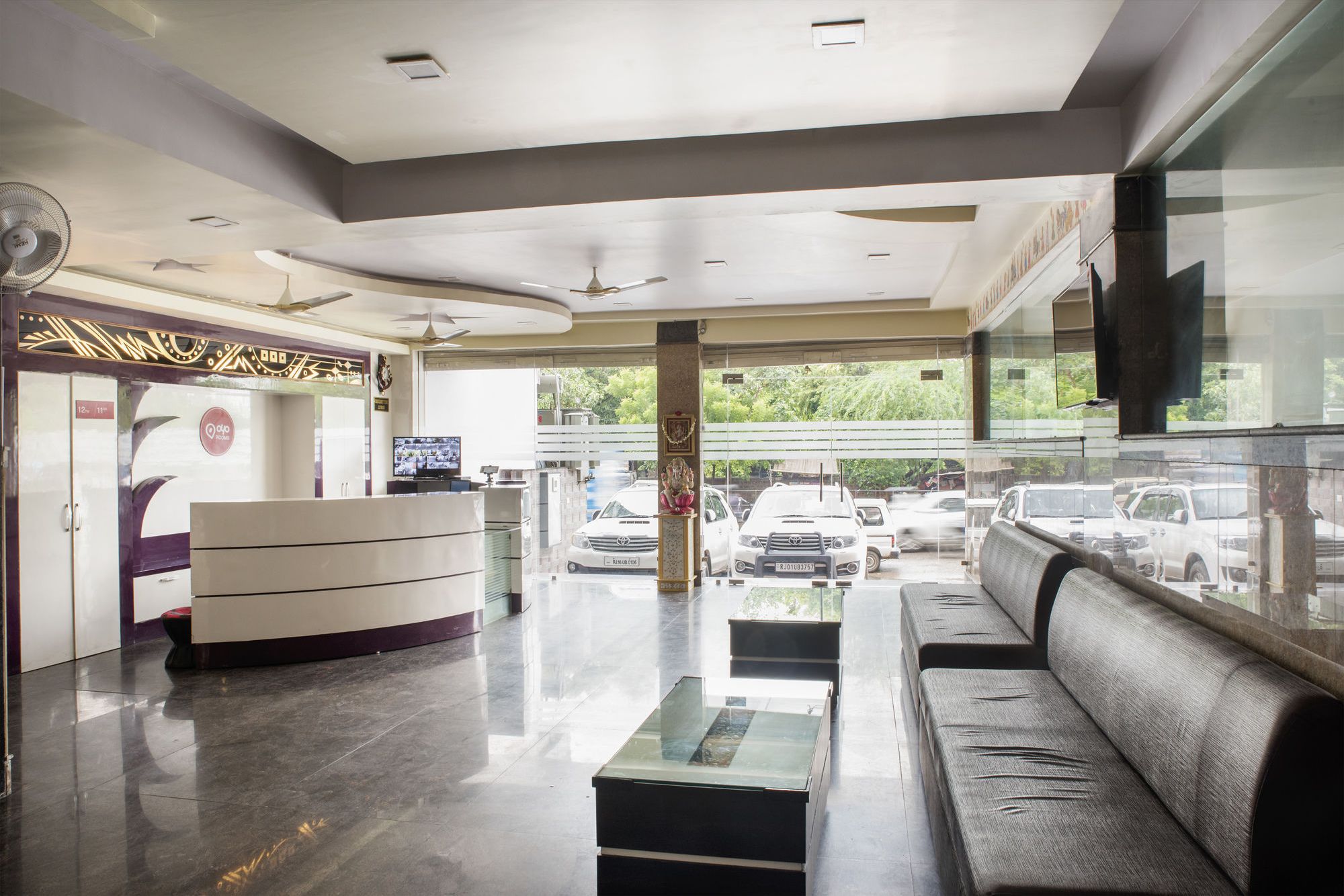 A reception area with a counter, seating, and a view of parked cars outside.