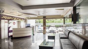 A reception area with a counter, seating, and a view of parked cars outside.
