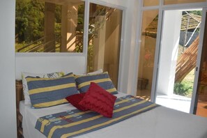A bedroom with a bed, pillows, and a view through a large window. - SMyleINN Farm Resort OPC (San Fernando)