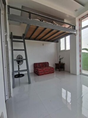 A room with a loft bed, a fan, a red sofa, and a window. - SMyleINN Farm Resort OPC (San Fernando)