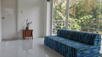 A modern room with a large window, a patterned sofa, and a small wooden table with a plant.