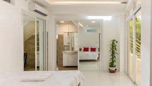 A modern bedroom with a bed, a bathroom with a sink, and a potted plant. - SMyleINN Farm Resort OPC (San Fernando)
