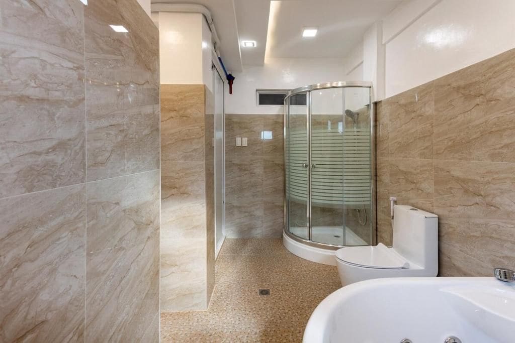 Un baño moderno con cabina de ducha de vidrio, una bañera blanca y paredes de mármol.