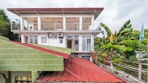 A two-story building with a red roof, a balcony on the upper floor, and a staircase leading to the entrance. - SMyleINN Farm Resort OPC (San Fernando)