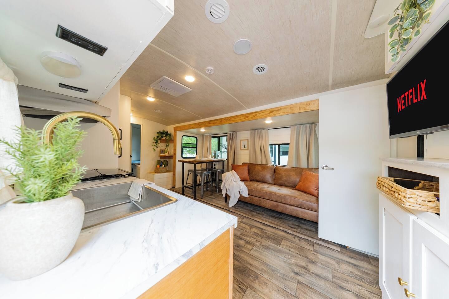 Un espacio habitable compacto con kitchenette, un sofá, un televisor y una zona de comedor.