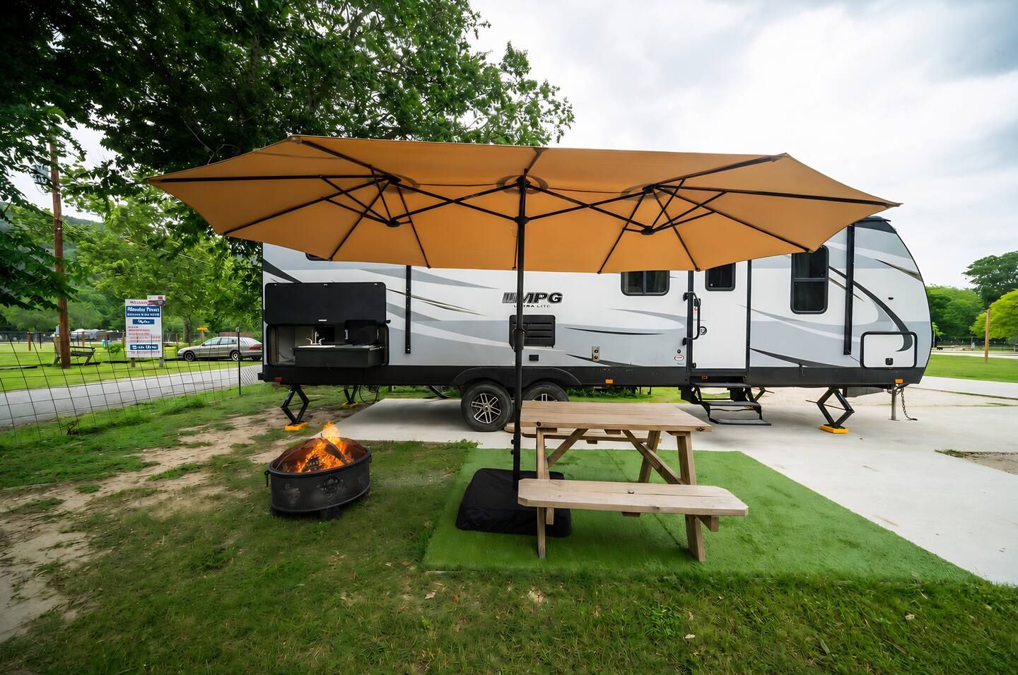 Ein Wohnmobil mit Grillplatz, Picknicktisch und Feuerstelle.