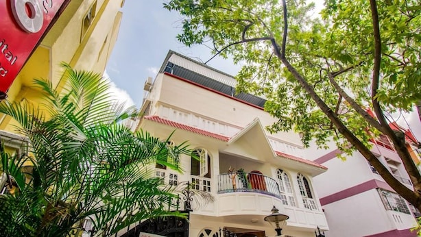 A multi-story building with balconies, a sign for '2D Reproductions,' and a palm tree in the foreground. - OYO Rooms Marathahalli Junction (Bengaluru)