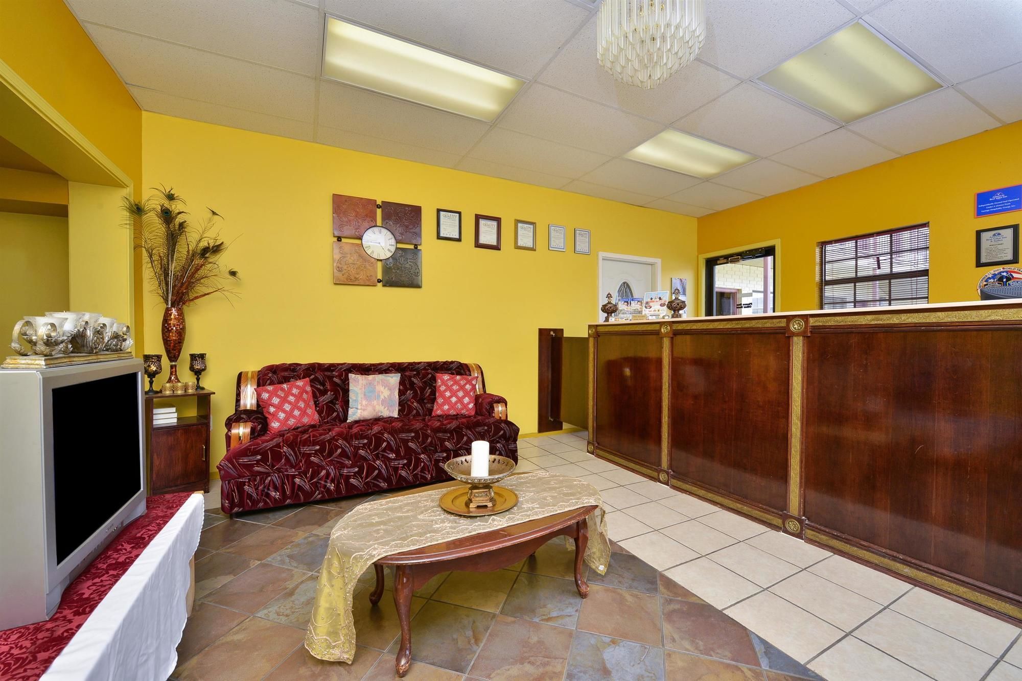 A reception area with a sofa, a television, a reception desk, and a wall with framed certificates.