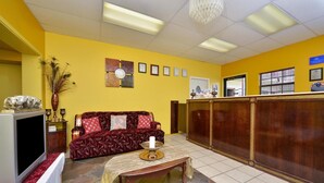 Ein Empfangsbereich mit einem roten Sofa, einem Holztresen und einem Fernseher.