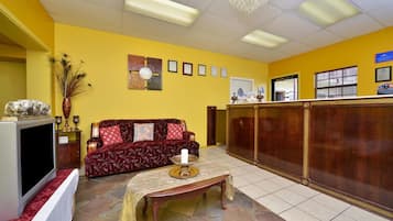 A reception area with a sofa, a television, a reception desk, and a wall with framed certificates.