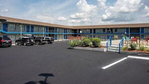 Ein Motel mit Parkplatz, blauer Fassade und blauem Himmel.