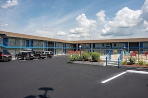A motel with a parking lot, a blue exterior, and a clear sky. - Americas Best Value Inn & Suites - Russellville (Russellville)