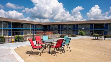 A motel with a courtyard featuring outdoor seating and a fenced area.