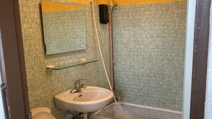Un baño pequeño con inodoro, lavamanos y ducha.