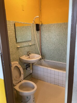 Un baño pequeño con inodoro, lavamanos y ducha.