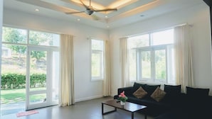 A spacious living room with a black sofa, a coffee table, and a ceiling fan. - Villa Panda (Phu Thuy)
