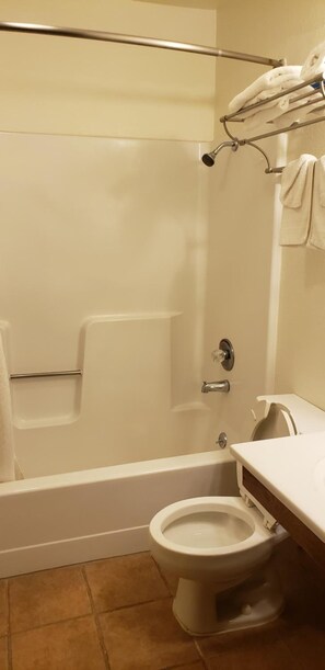 A bathroom with a bathtub, toilet, and a towel rack. - Americas Best Value Inn Burlington (Burlington)