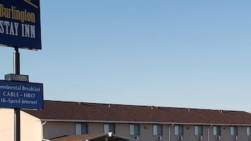 A motel with a sign for Burlington Stay Inn and amenities including continental breakfast, cable, HBO, and high-speed internet.