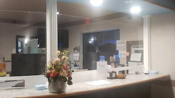 A reception desk with a vase of flowers, a counter with various items, and a view of the reception area.