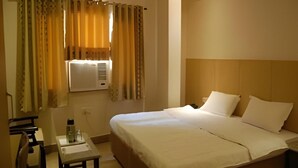 A hotel room with a bed, bedside table, and a desk with a chair. - OYO Rooms 80 Feet Road (Kanpur)
