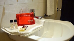 A bathroom sink with toiletries and a red bag on a towel. - OYO Rooms 80 Feet Road (Kanpur)
