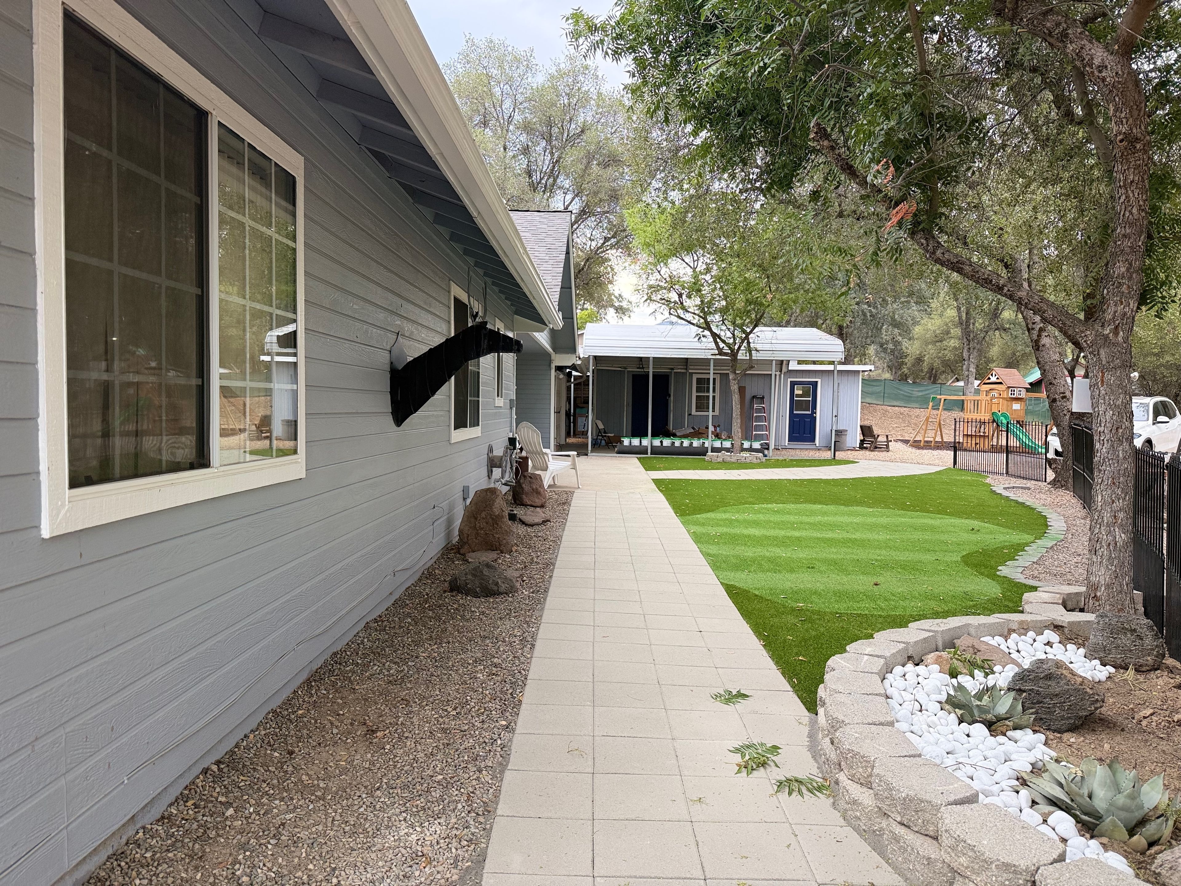 A residential property with a paved walkway, a lawn, and a play area with a slide.