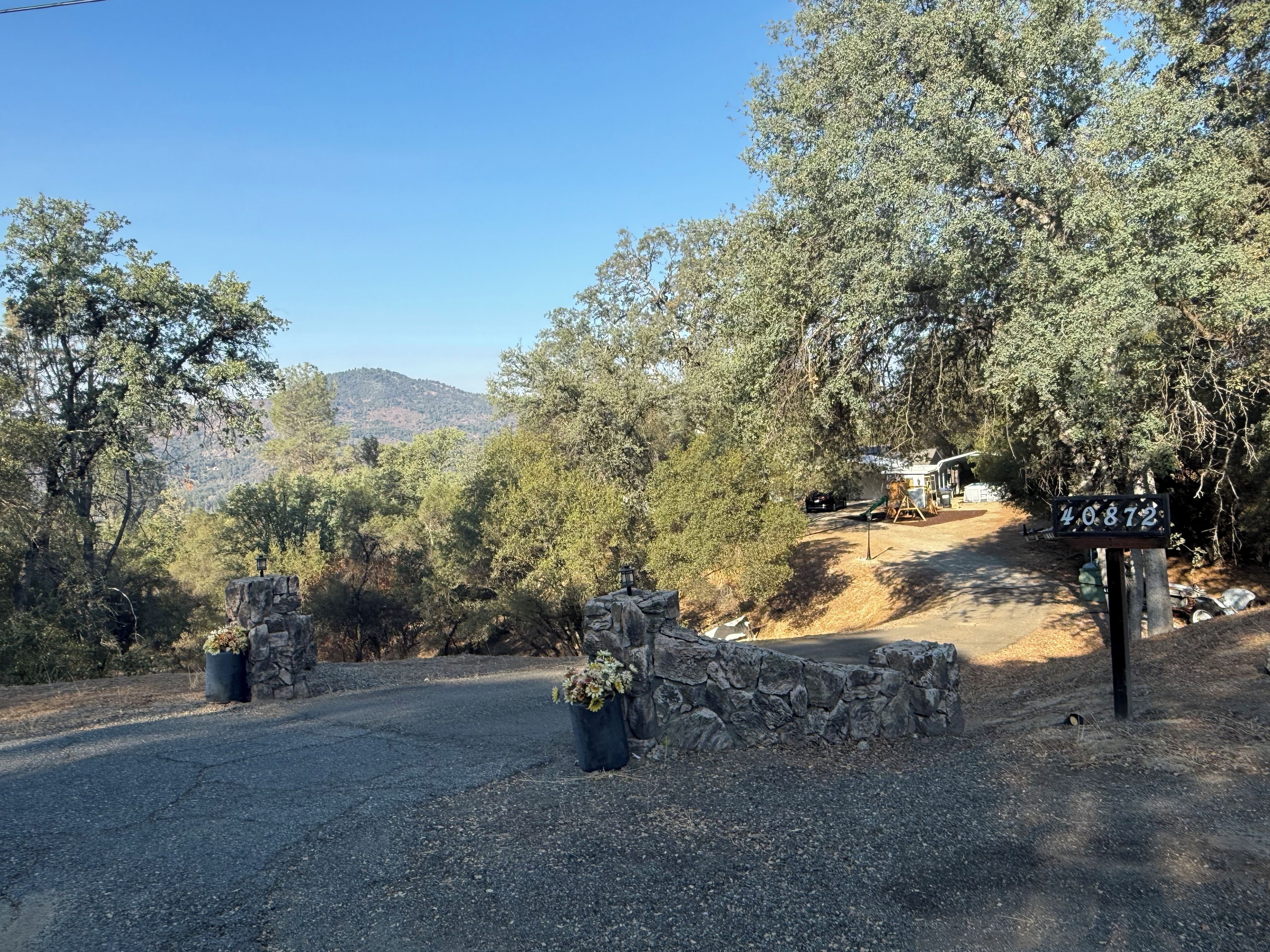 A driveway leading to a house with a stone wall and a sign displaying the number 40872.