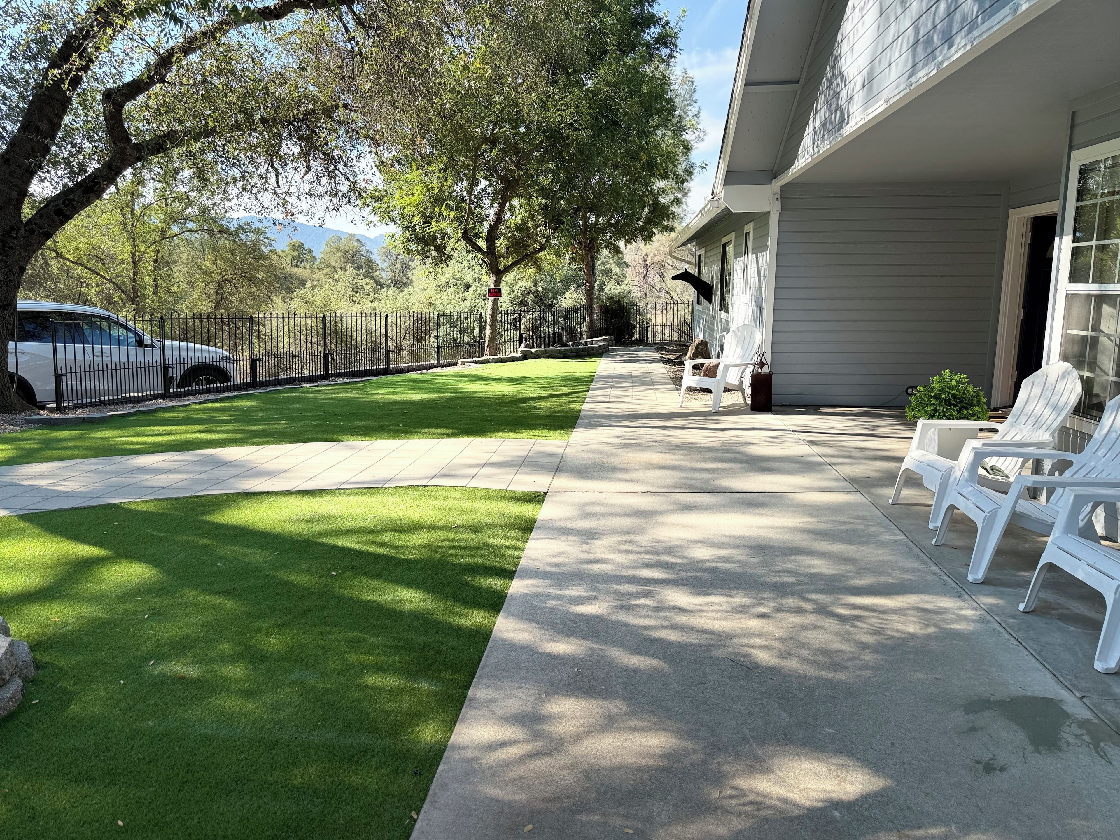 A residential property with a paved driveway, a lawn, and outdoor seating chairs.