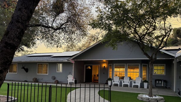 A residential house with a front porch, a fenced yard, and a tree. - Relaxing Yosemite house w. Gorgeous Views, Hot tub, Sauna, Pool, Games, Gym, EV (Oakhurst)