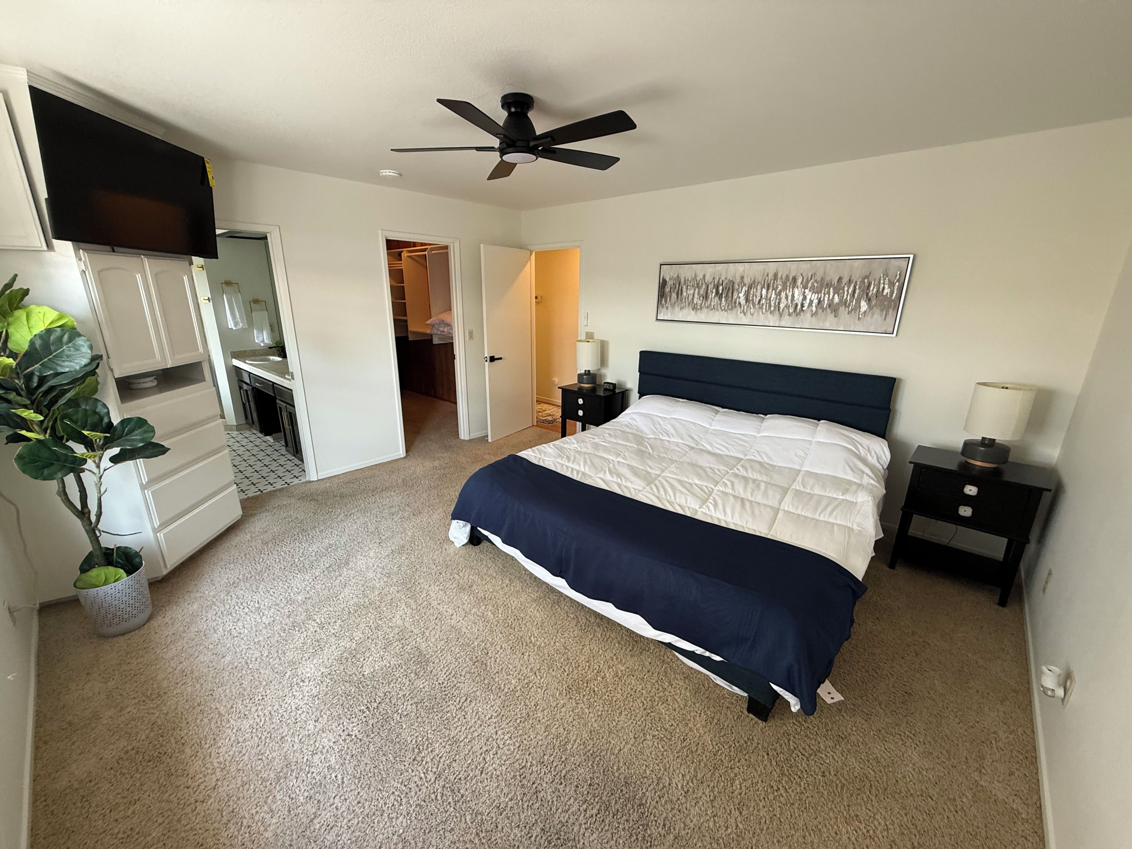 A bedroom with a bed, a ceiling fan, a nightstand, a lamp, and a closet.