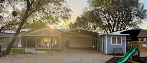 A residential area with a gravel driveway, a garage, and a small play structure with a slide.