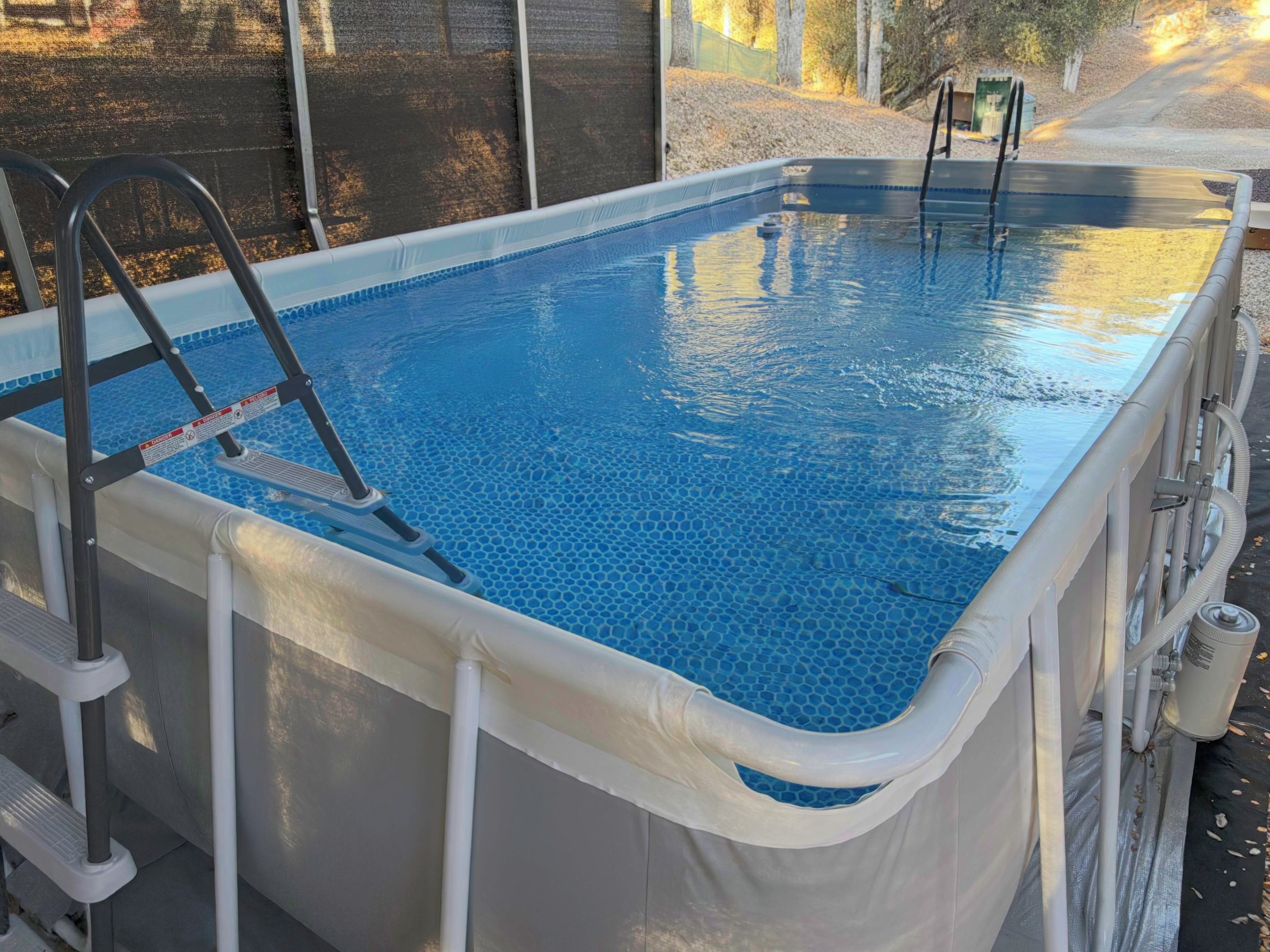 An above-ground swimming pool with a ladder and safety rail.
