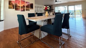 A dining area with a wooden table and teal chairs, a vase with flowers, and a large window with a view. - Relaxing Yosemite house w. Gorgeous Views, Hot tub, Sauna, Pool, Games, Gym, EV (Oakhurst)