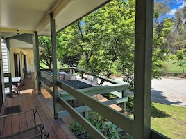 Un espacio al aire libre techado con terraza de madera, mesas y sillas.