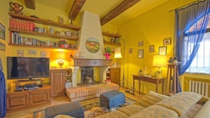 A cozy living room with a fireplace, bookshelves, a television, and a sofa. - Villa Sabrina (San Gimignano)