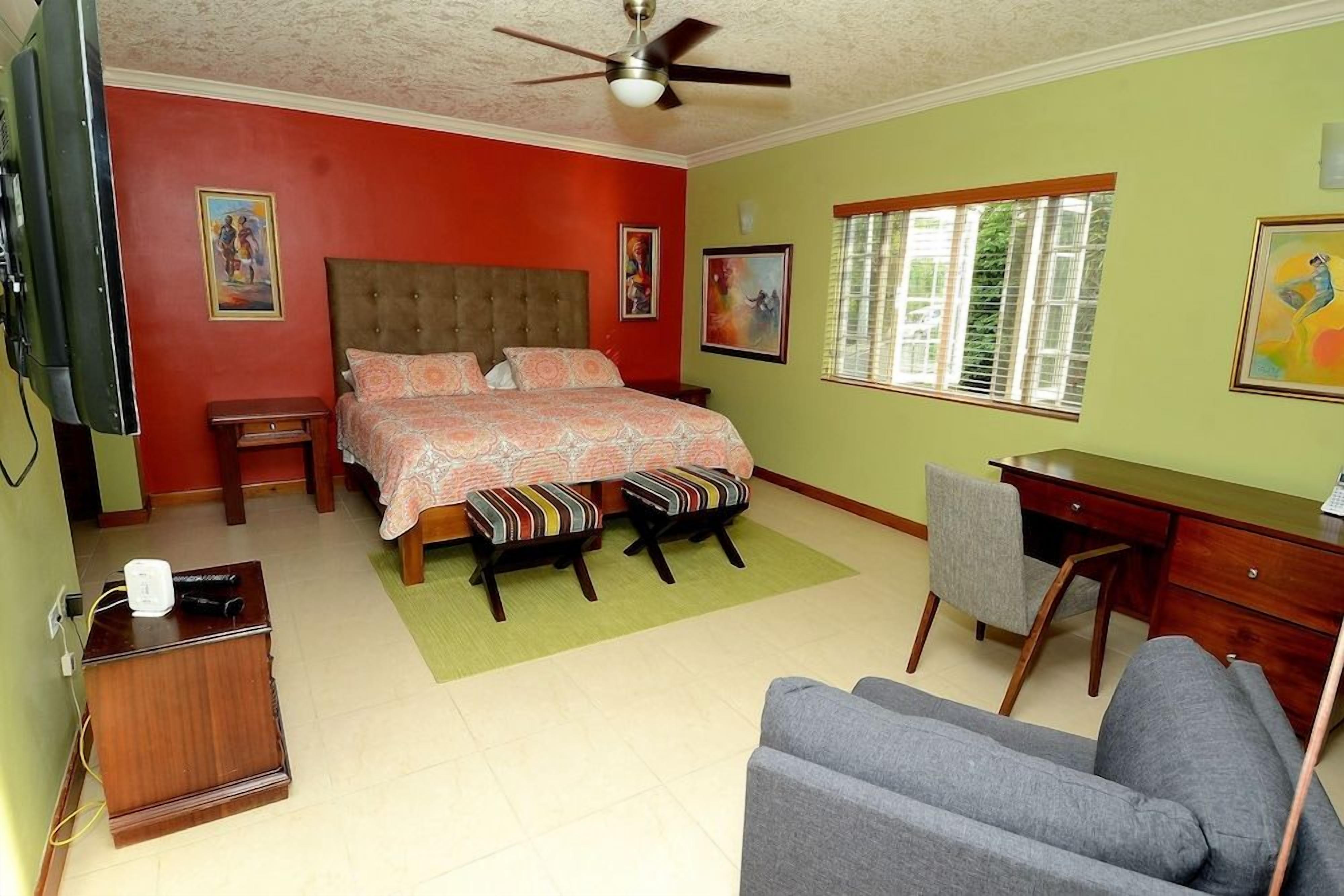 A bedroom with a bed, a desk, a chair, and a television.