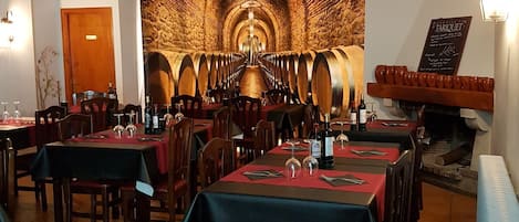 A restaurant interior with tables set for dining, a wall mural of wine barrels, and a display of poinsettia flowers.