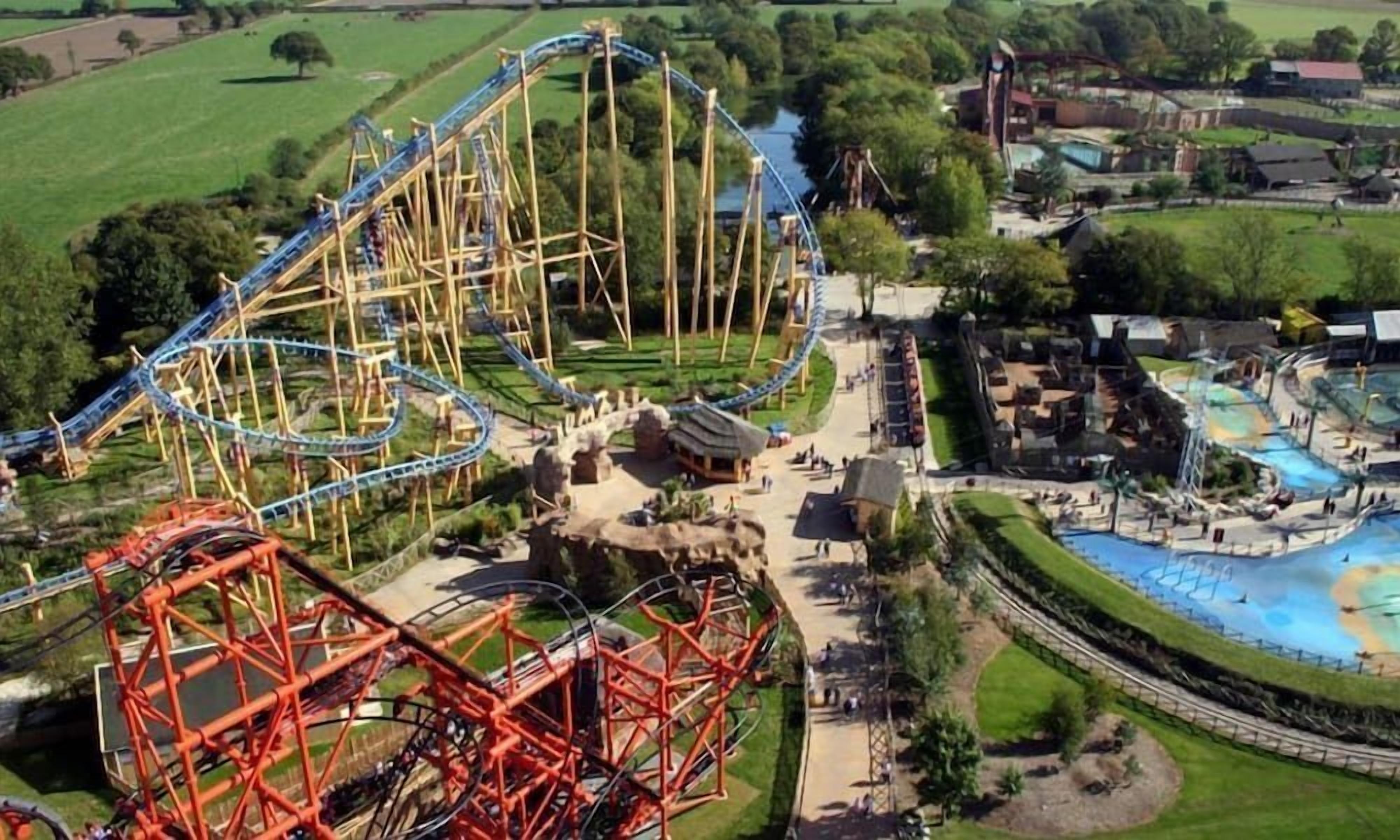 Vue aérienne d’un parc d’attractions avec des montagnes russes et un parc aquatique.