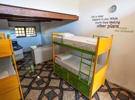 Quarto com beliche, uma citação inspiradora na parede, janela e escrivaninha.