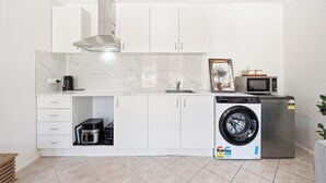 Una cocina compacta con lavadora integrada, microondas y cafetera.