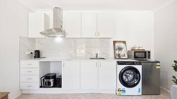 A compact kitchen with a built-in washing machine, a microwave, and a coffee maker.