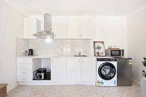 Een compacte keuken met een inbouw wasmachine, een magnetron en een koffiezetapparaat.