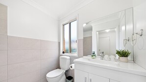 Un baño moderno con inodoro, lavamanos y espejo.