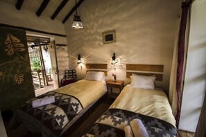 Habitación con dos camas, cabecero de madera, mesita de noche con lámpara y luz de pared.
