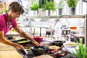 Montaje de bufé con diversas opciones de comida y una persona atendiendo.