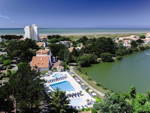 Un resort con piscina, vista a la playa y un cuerpo de agua.