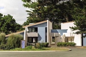 Un bâtiment moderne doté d’un toit plat, d’un balcon et d’une enseigne.