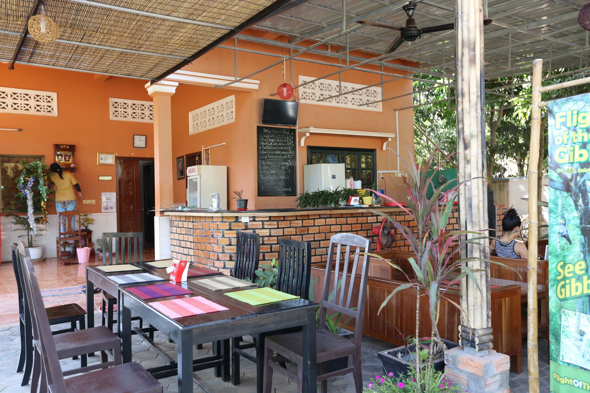 Un espacio al aire libre con mesas y sillas, una barra con refrigerador y un tablero de menú.