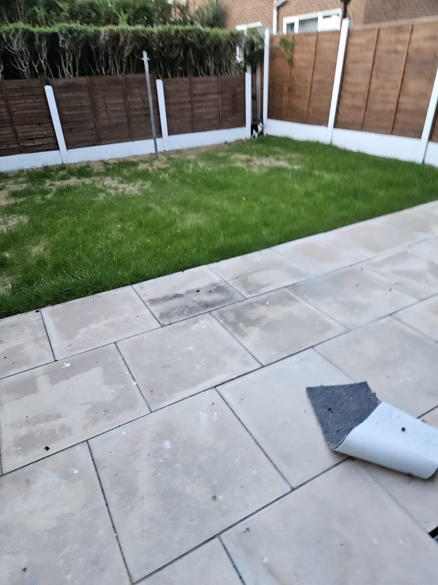 A patio area with a tiled floor and a grassy lawn.