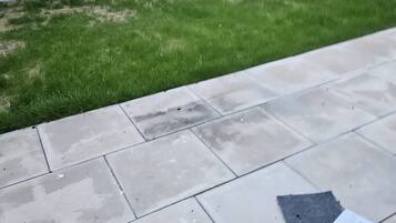 A patio area with a tiled floor and a grassy lawn.